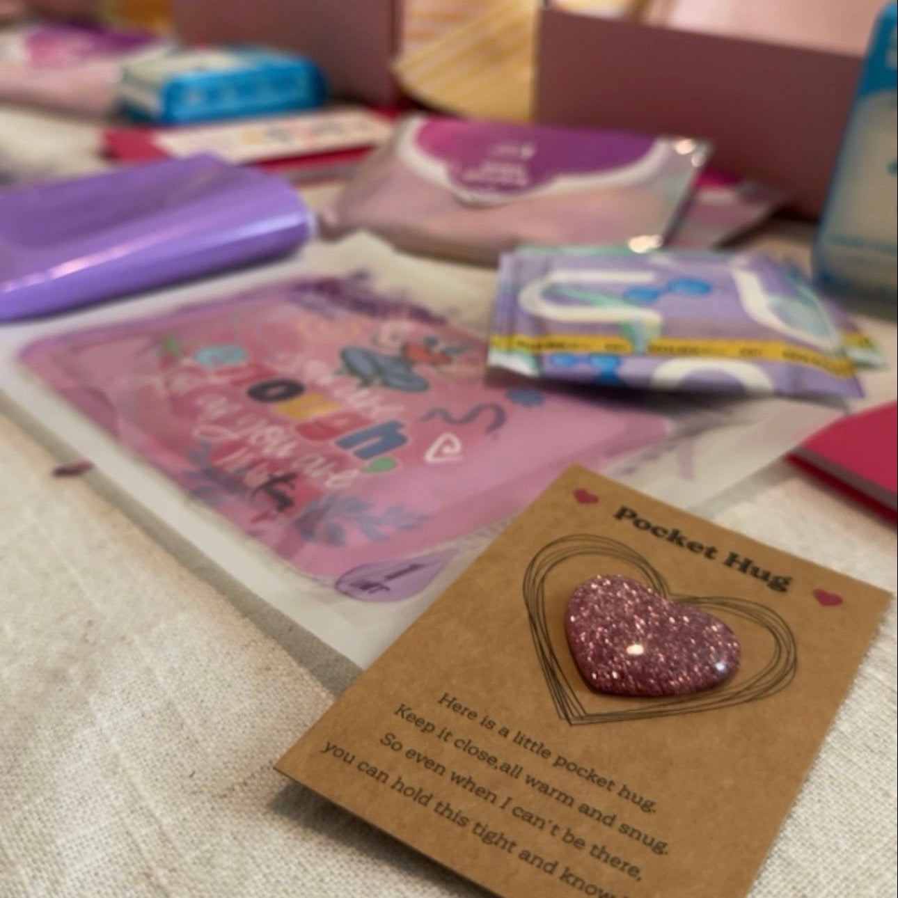 A pink glitter heart-shaped pocket hug pin displayed 